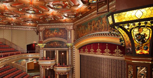 Audience seats face an ornate, gold-detailed stage under murals and stained glass lights in a historic haunted NYC theater.