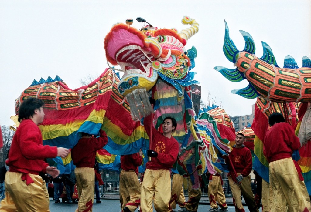 Performers in red shirts and gold pants carry a vibrant dragon costume during a Chinese New Year parade in New York City.
