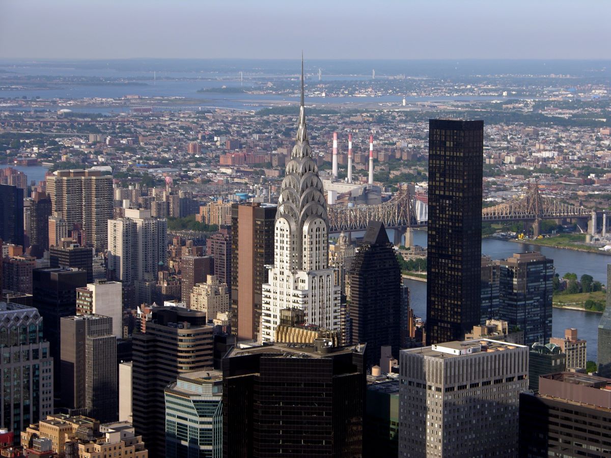 The art deco Chrysler Building stands tall among Manhattan skyscrapers, with the East River and Queensboro Bridge in the distance.