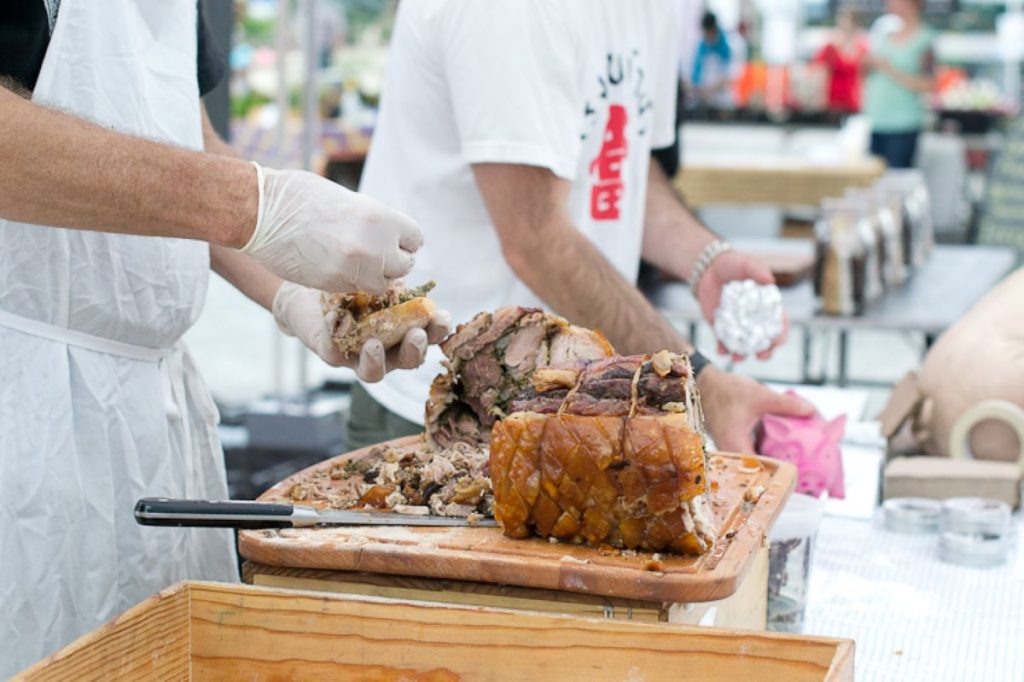 cooks making porshetta sandwiches at Smorgasburg market. 