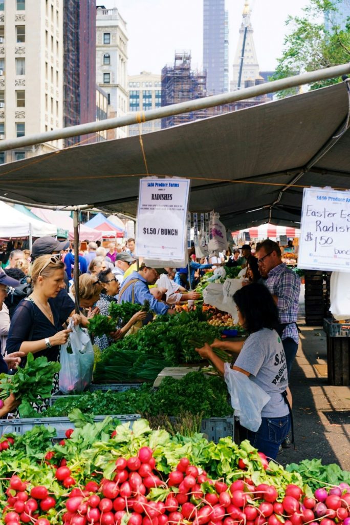 people shopping at an outdoor produce market in NYC. 
