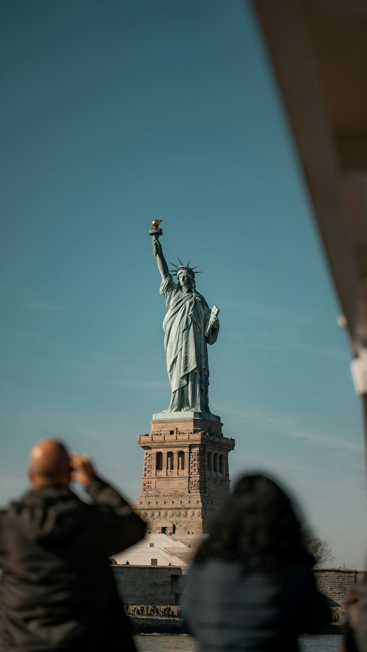 Tourists taking photos of the Statue of Liberty.