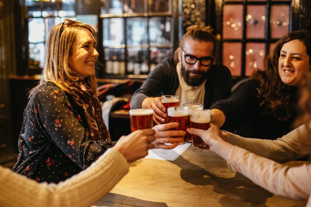 A group of friends raise pints of beer in a cheerful toast at a cozy pub, enjoying conversation and laughter.