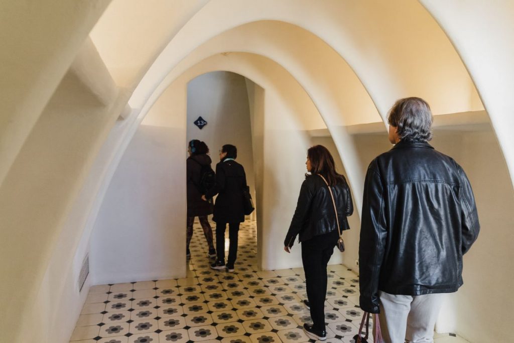 Guests walk through the arched hallways of Casa Batlló, crossing the beautifully decorated floral floor.