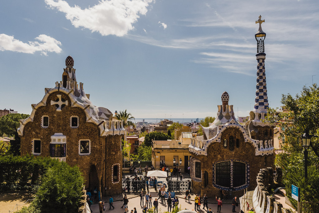 View of Gaudi's fanciful Parc Guell park in Barcelona, Spain from above on a bright summer day with visitors below