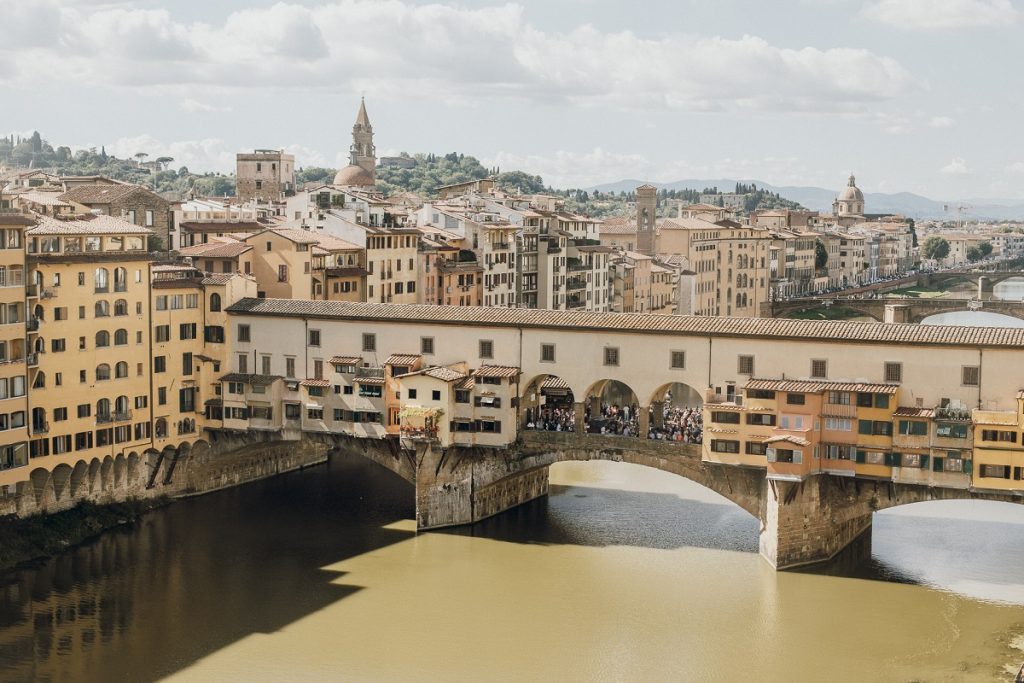 Vasari Corridor and bridge in Florence filled with people over the Arno river on a summer day