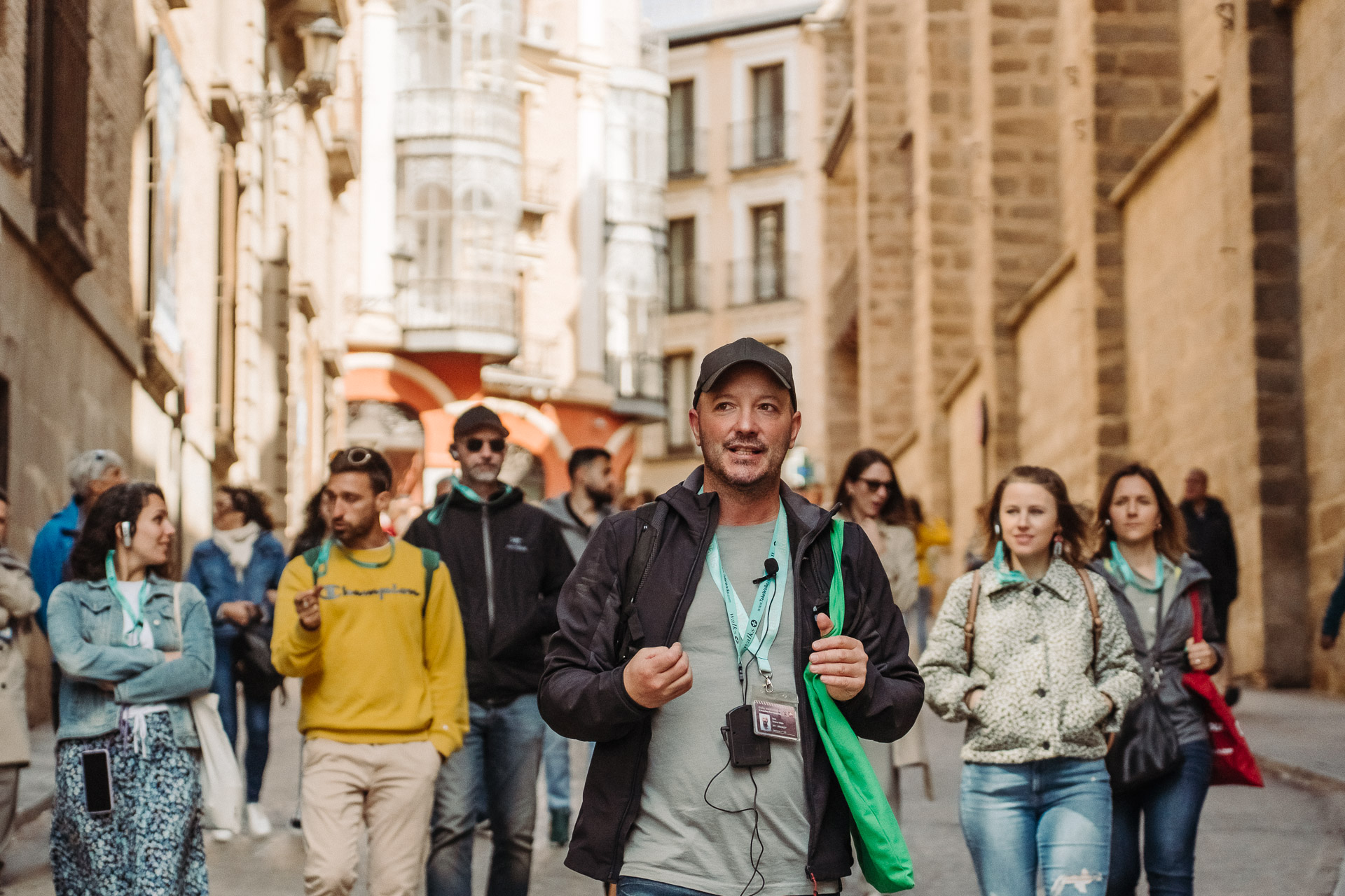 Walks tour guide with green tote bag leads a group of guests through the streets of a historic city