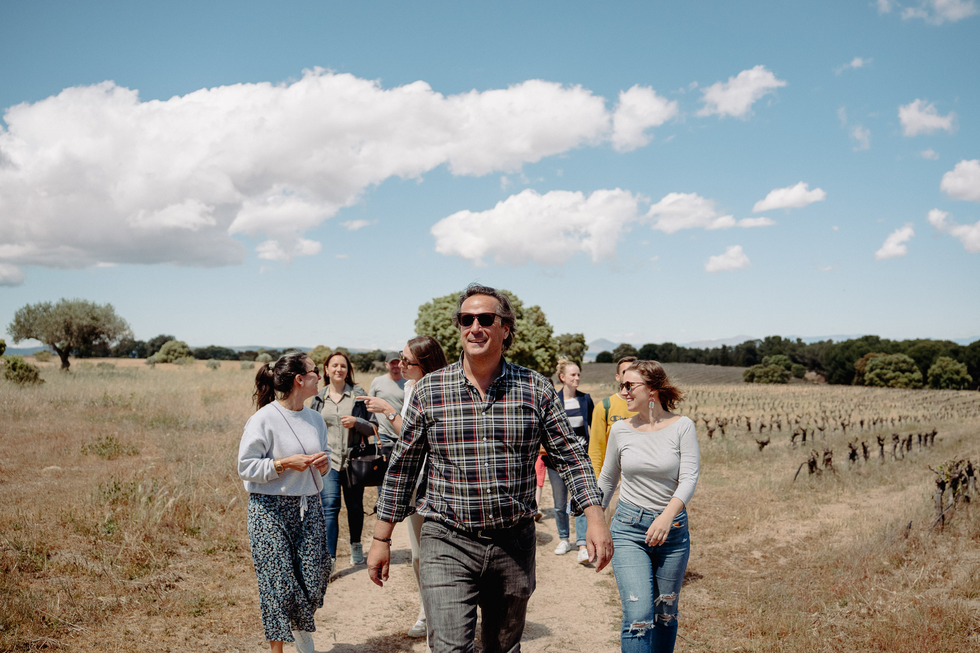 Winemaker leads a group of guests through the vineyards in early spring at an outdoor location in Spain