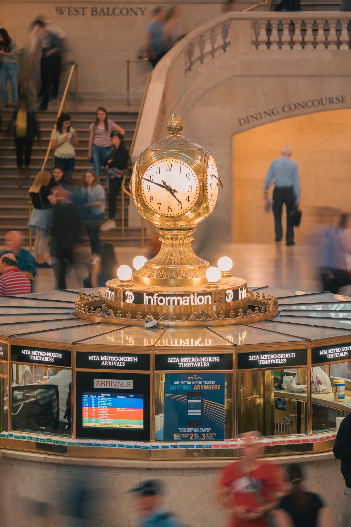 Golden Information Booth clock at grand central terminal wiht informational brochures and people