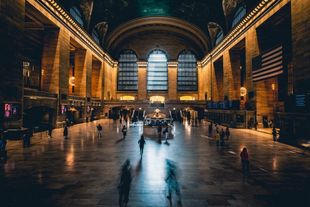 Dark Main concourrse with people and an american flag at Grand Central Terminal, NYC