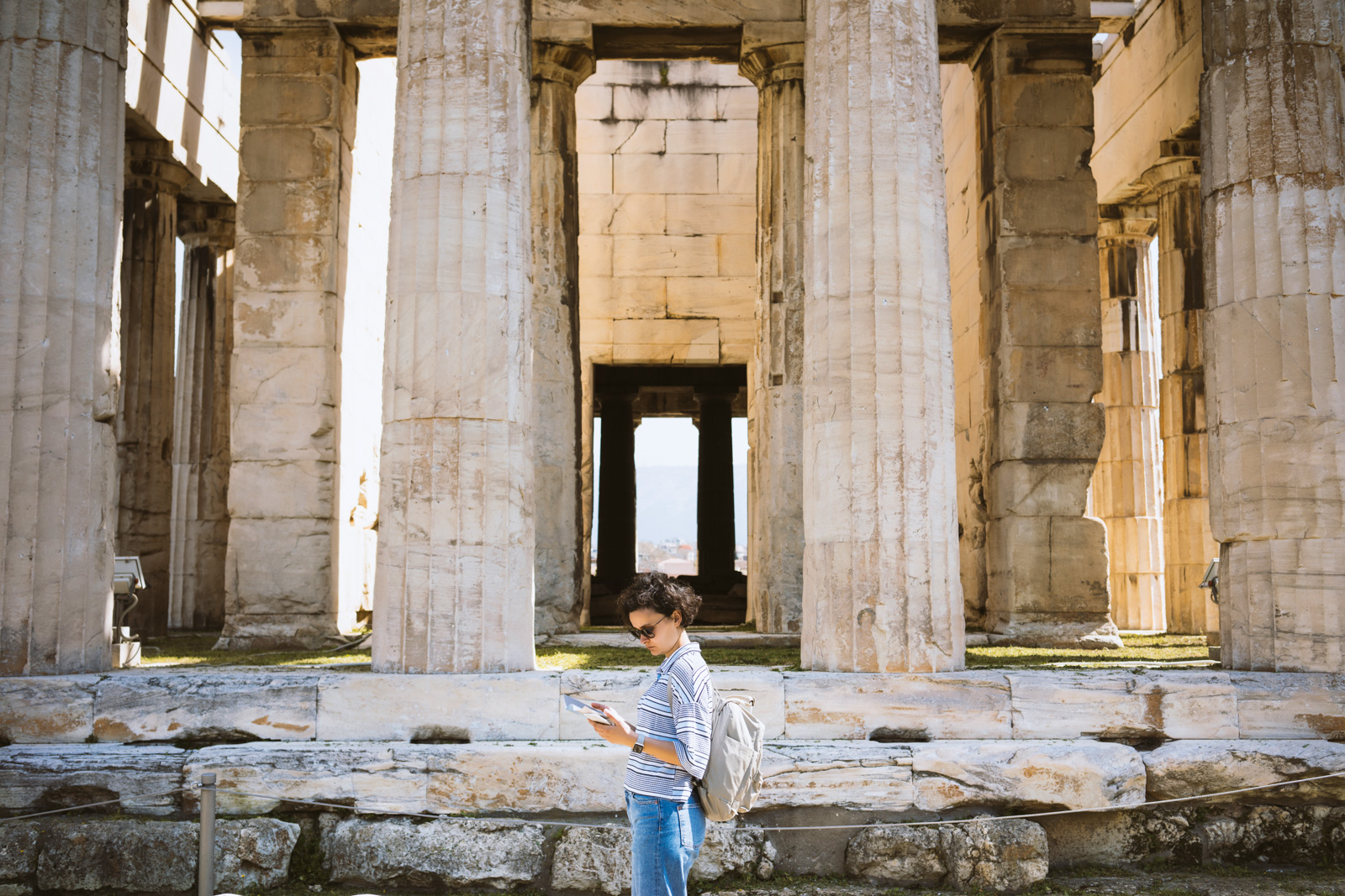 Woman looks at a guidebook in front of the Parthenon's columns in Athens, Greece