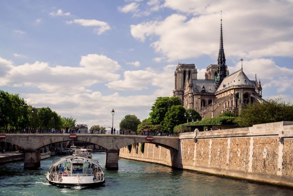 A back view of Paris's Notre Dame, and a view of a boat cruising down the Seine River