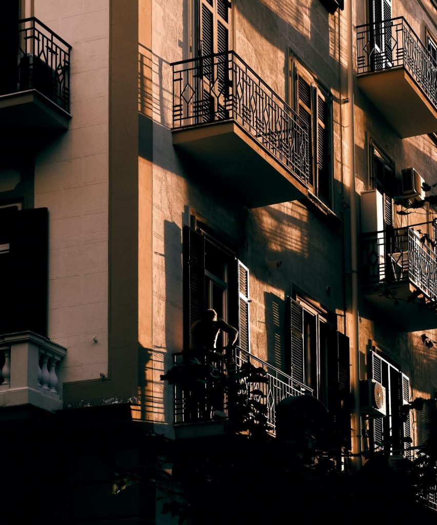 A building in Naples, Italy at sunset, where a man can be seen standing on one of the building's balconies.