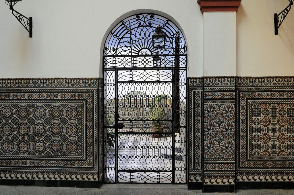 A view inside Hospital de los Venerables displaying the beautiful Andalusian tiles and doorframe.