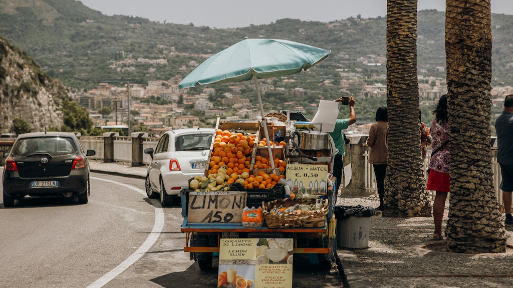 Truck selling lemons and oranges on a road along the Amalfi Coast with mountains in the distance