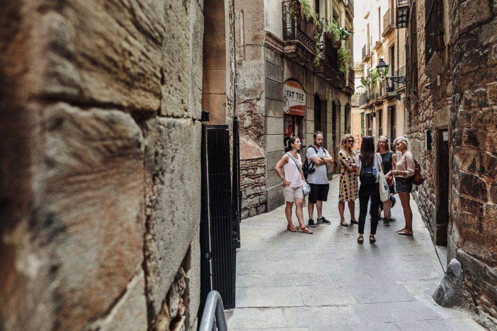 A group gathers with a guide on a small, narrow street in Barcelona