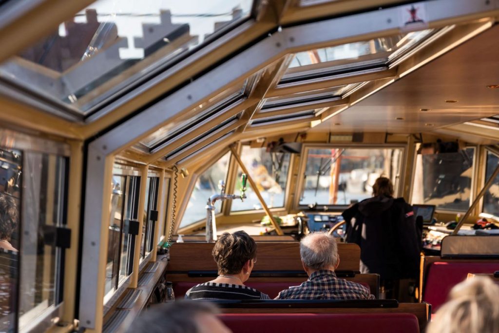 People take a boat tour through the canals of Amsterdam