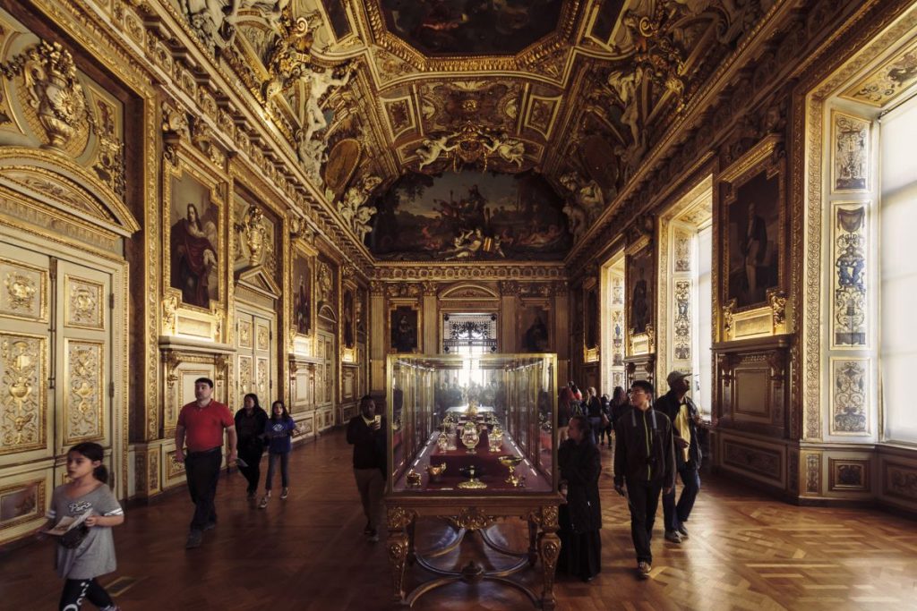 A hallway inside the Louvre museum, adorned with gold and paintings