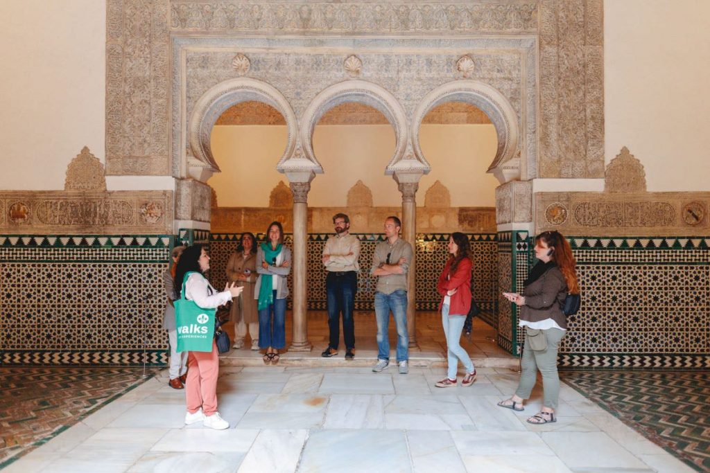 A group intently listen a guide as she shares history on Seville's Alcazar