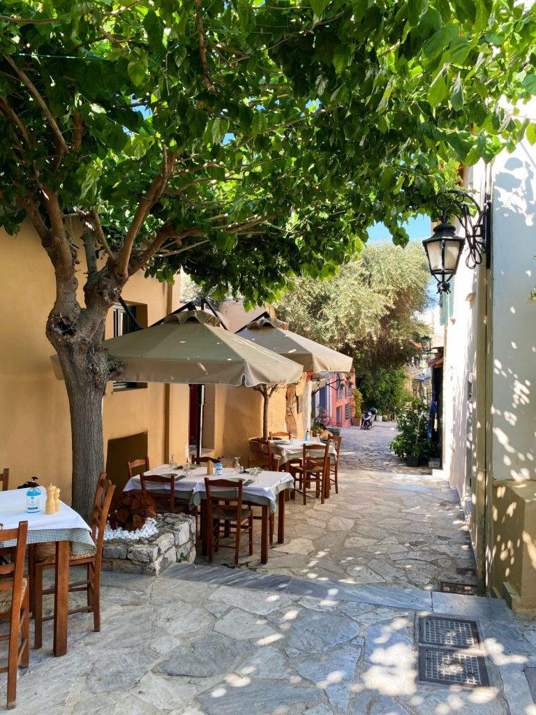 A small restaurant patio situated along a small set of stairs, on a small street in Athens, Greece.