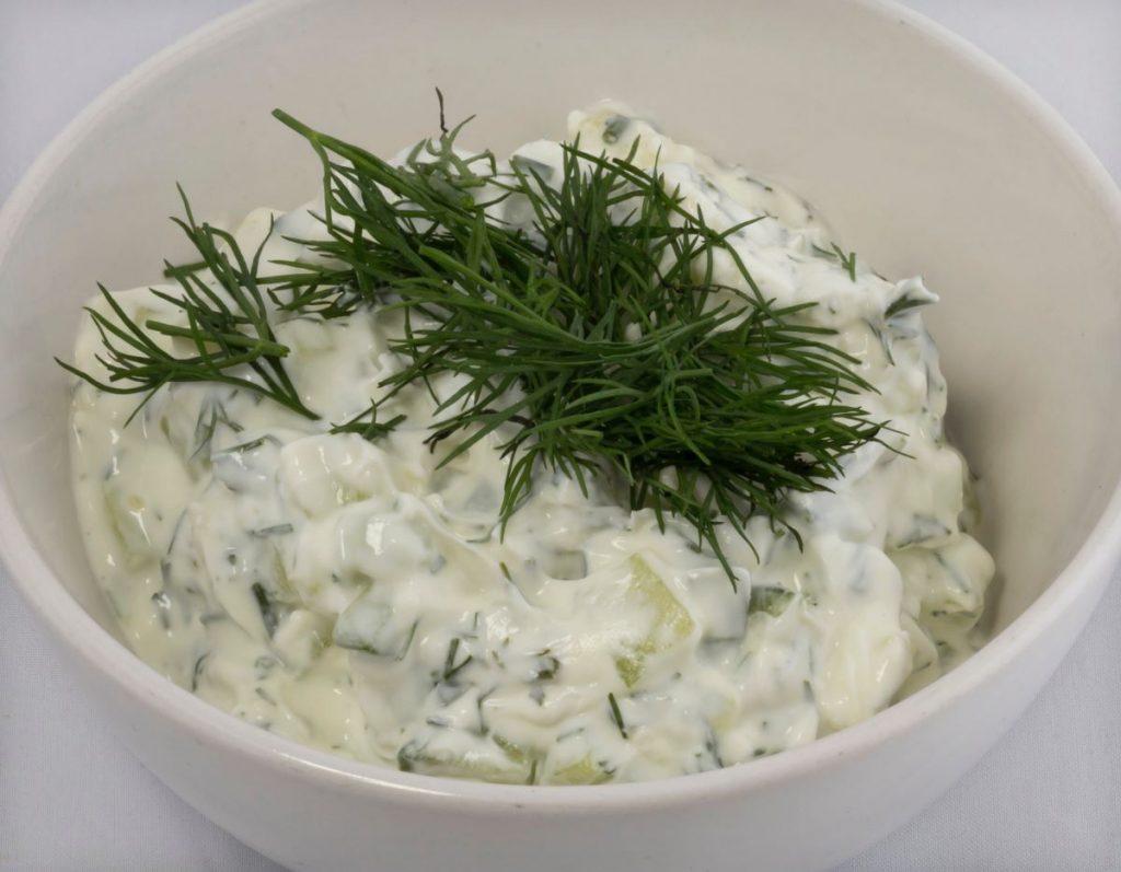 A bowl of vegan tzatziki with dill on top