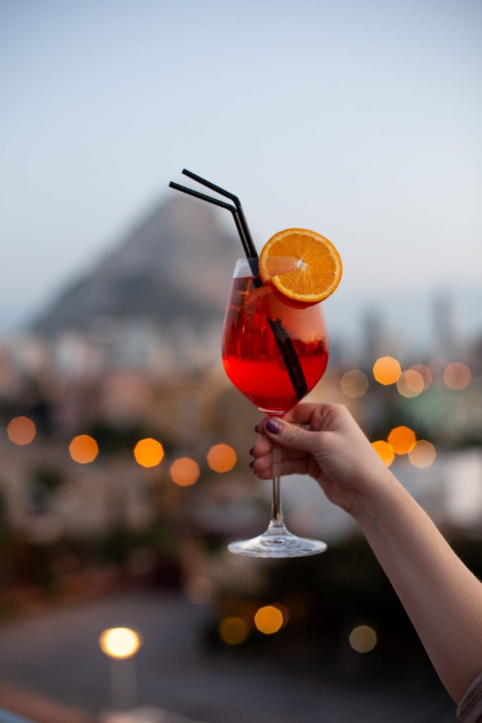 Someone holds an Aperol Spritz in the air, presumably for a cheers