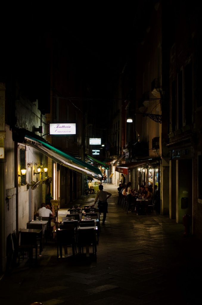 A side street in Venice filled with restaurants at night.