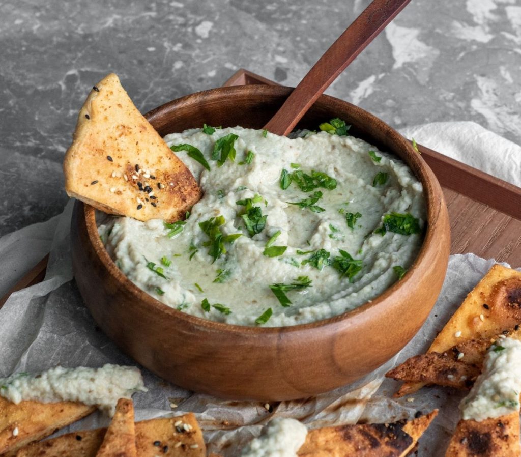 A bowl of baba ganoush with pita chips.