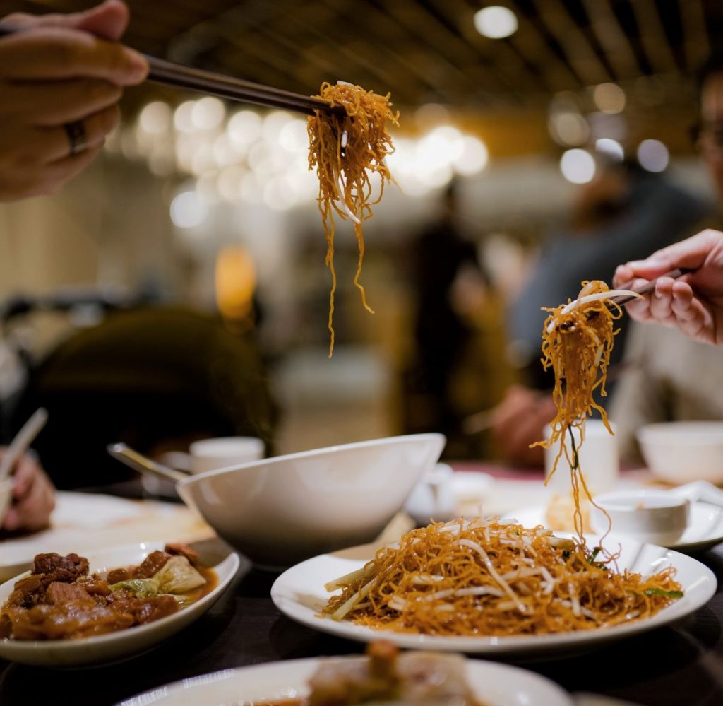People eating some Chinese food using chopsticks