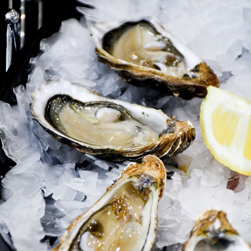 A plate of fresh oysters with a lemon wedge