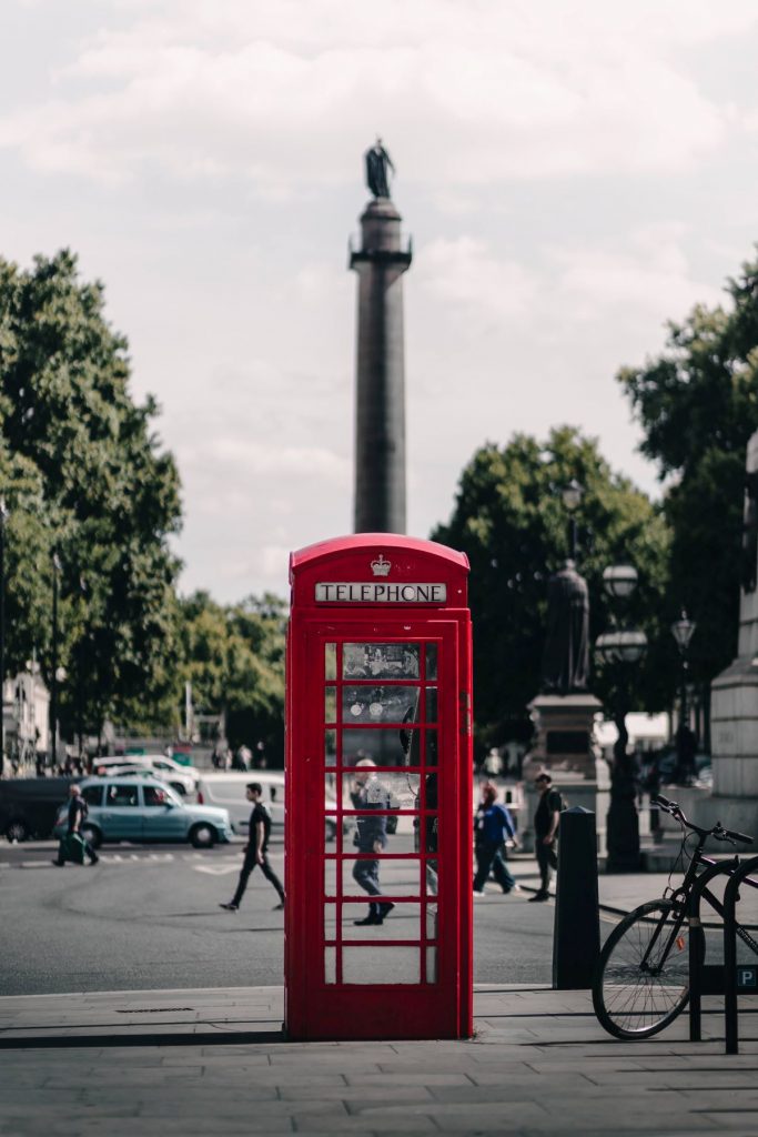 A red phone booth sitting on the side of a road
