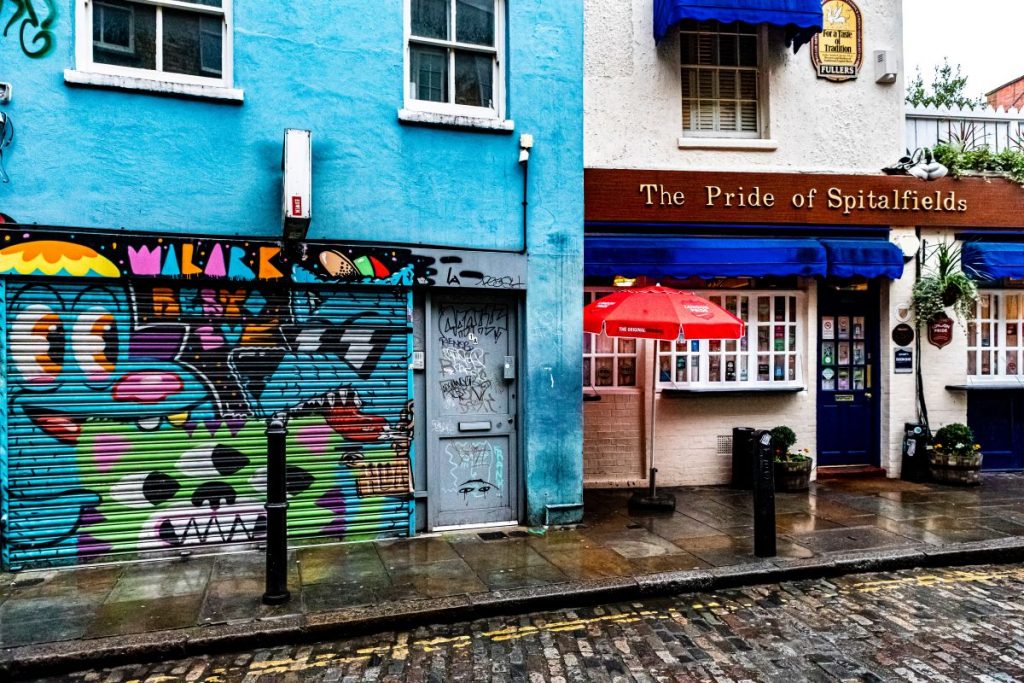 A building filled with grafitti and street art, located next to a restaurant