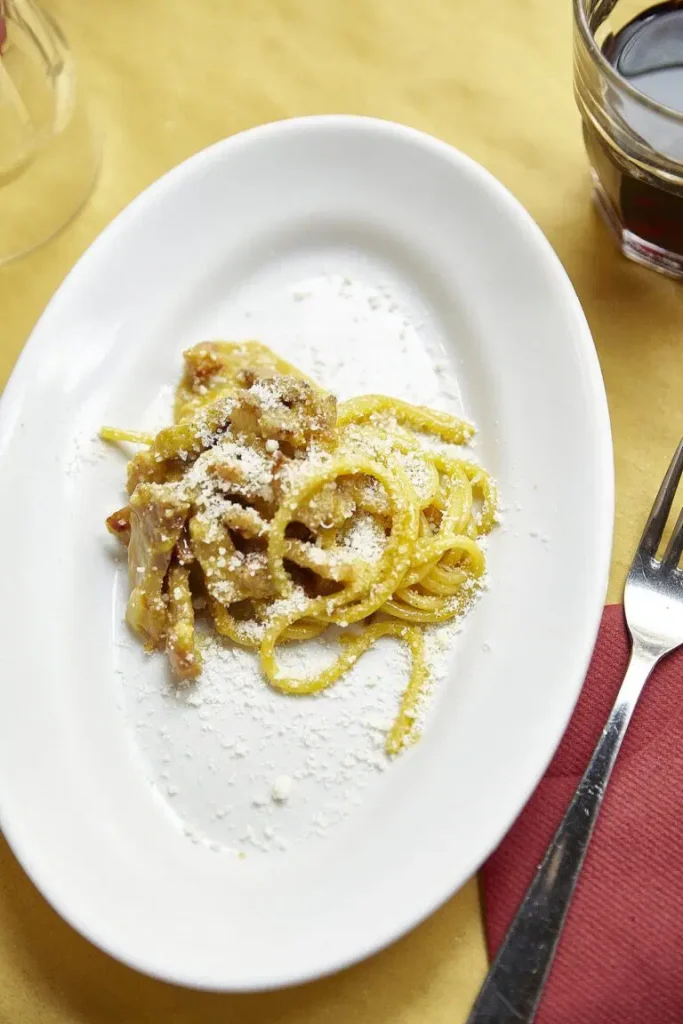 A plate of pasta with ham and grated cheese