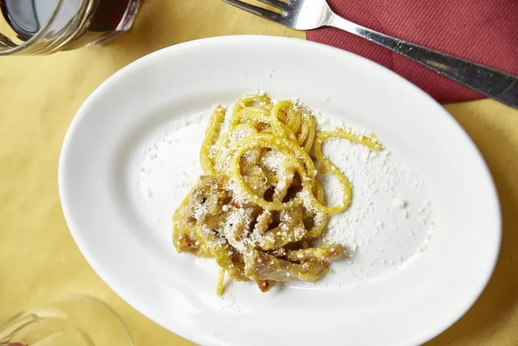 A plate of pasta with ham and grated cheese