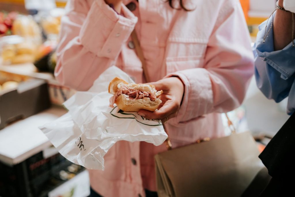 A woman holding a sandwhich with mortadella