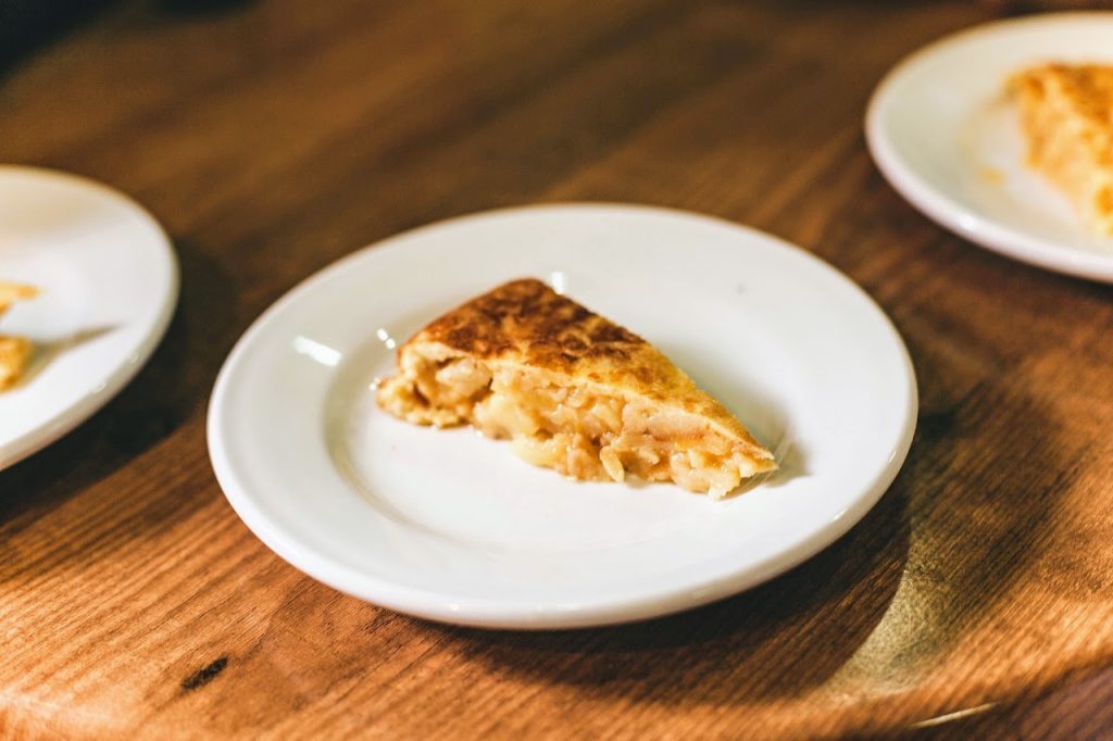 White plate with a slice of Spanish tortilla, or potato omelette