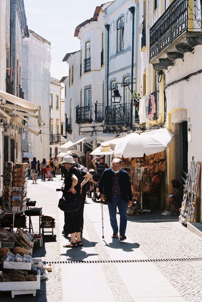 people walking down a small street on a sunny day