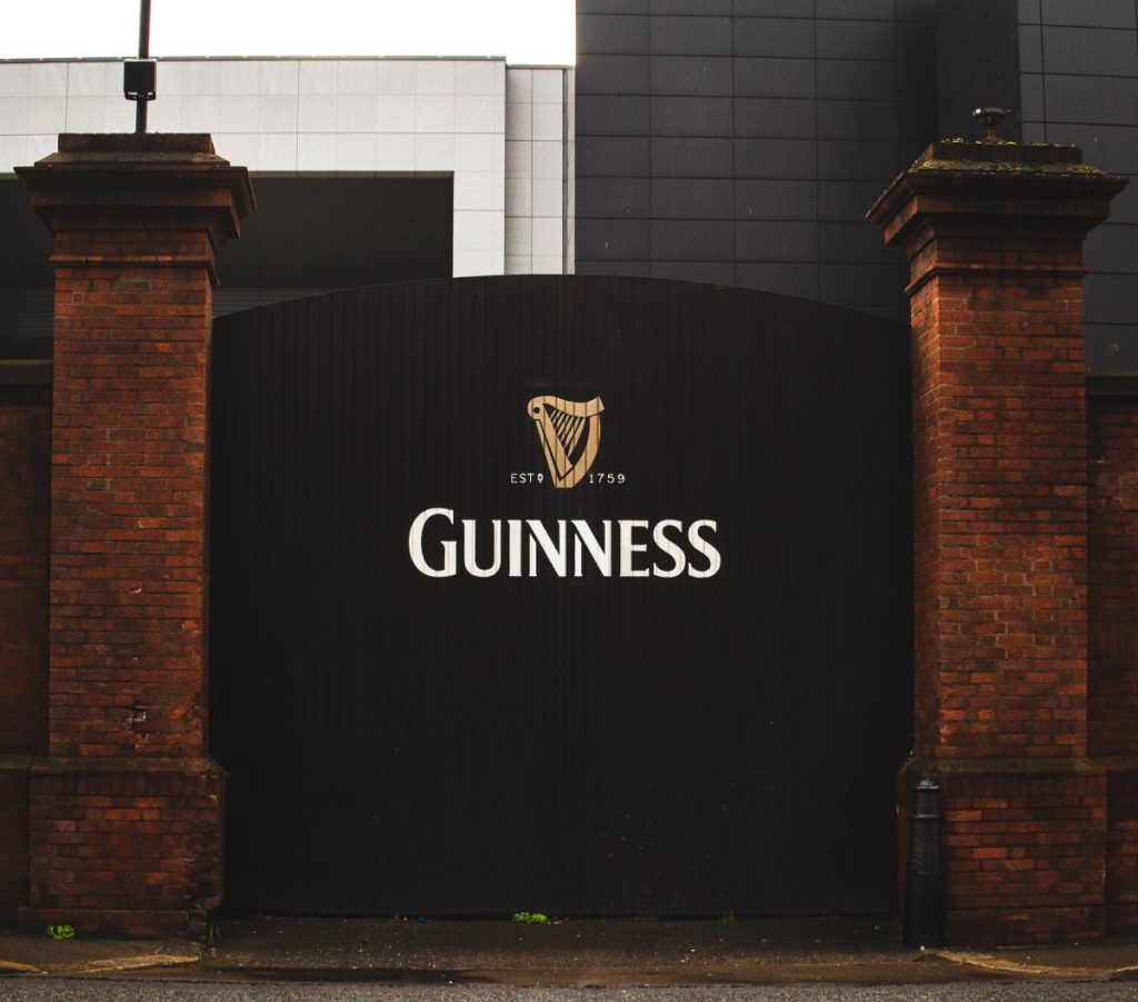 A large black Guinness gate with a gold harp logo stands between brick pillars at the St. James’s Gate Brewery in Dublin.