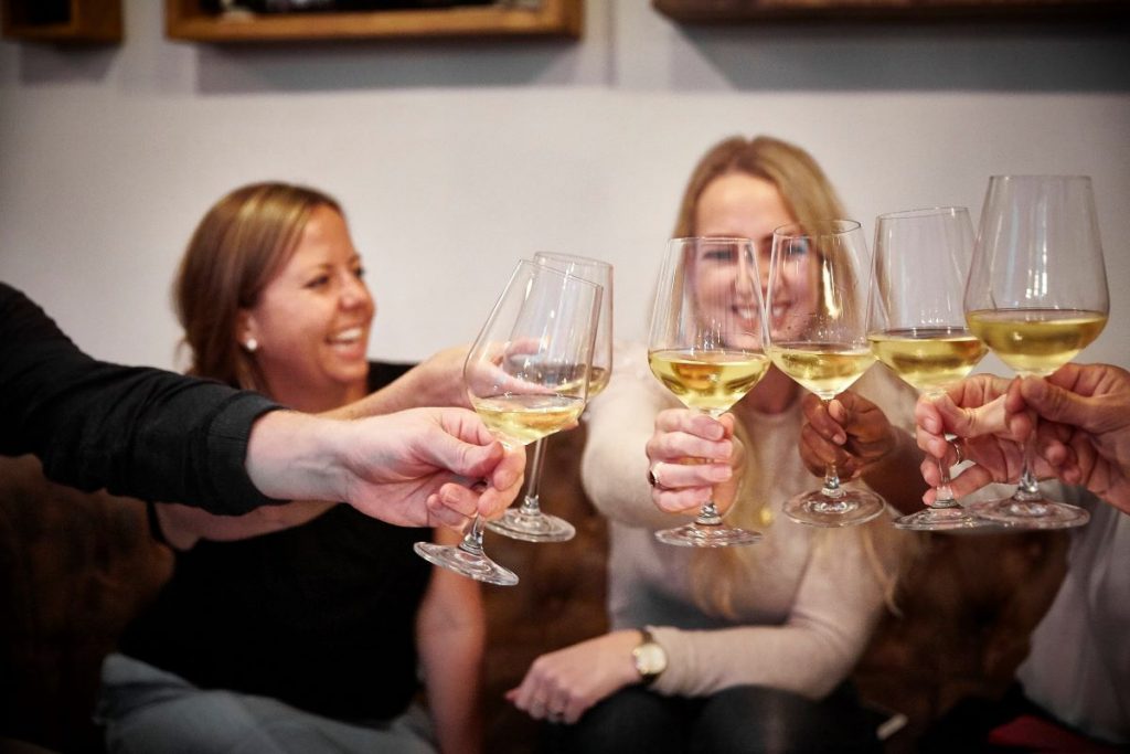 people doing a cheers with glasses of white wine