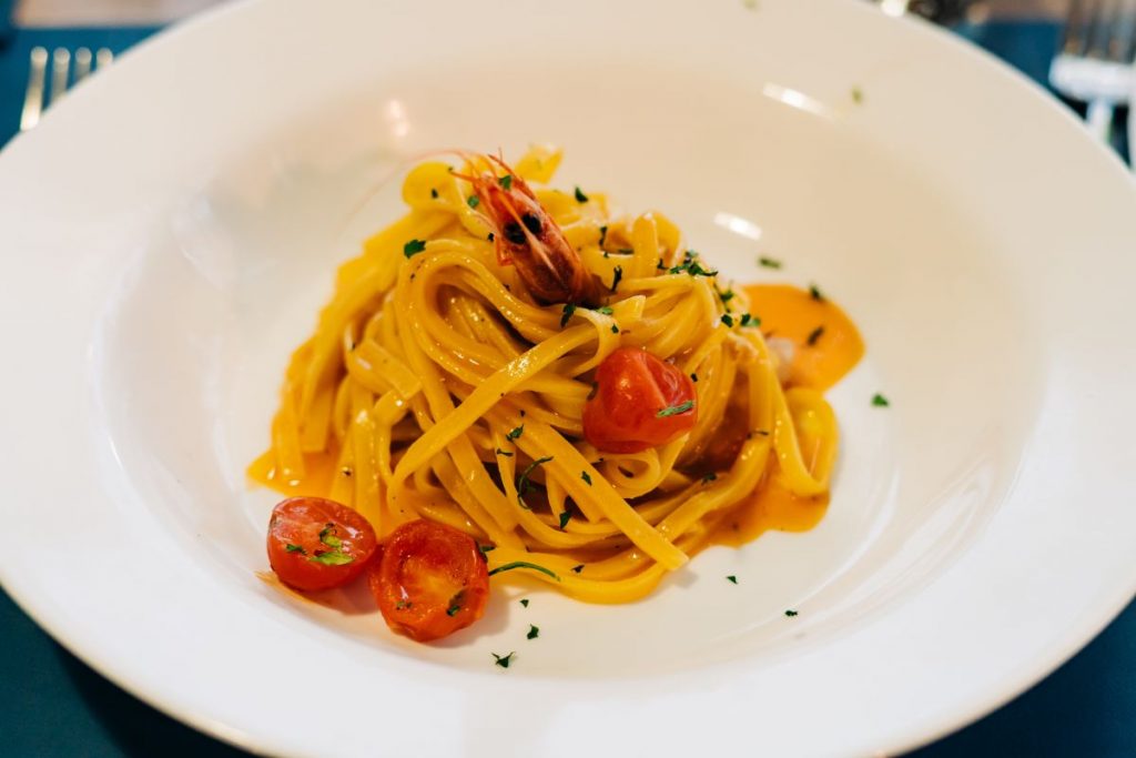 a plate of pasta with shrimp and tomatoes