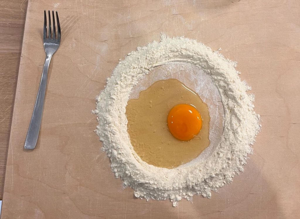 Flour, egg and fork on a board set for pasta making