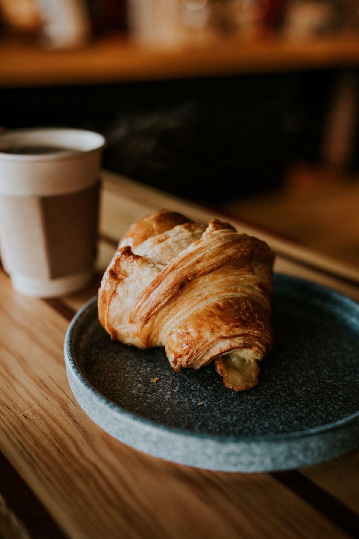 Closeup of croissant and coffee in the background.