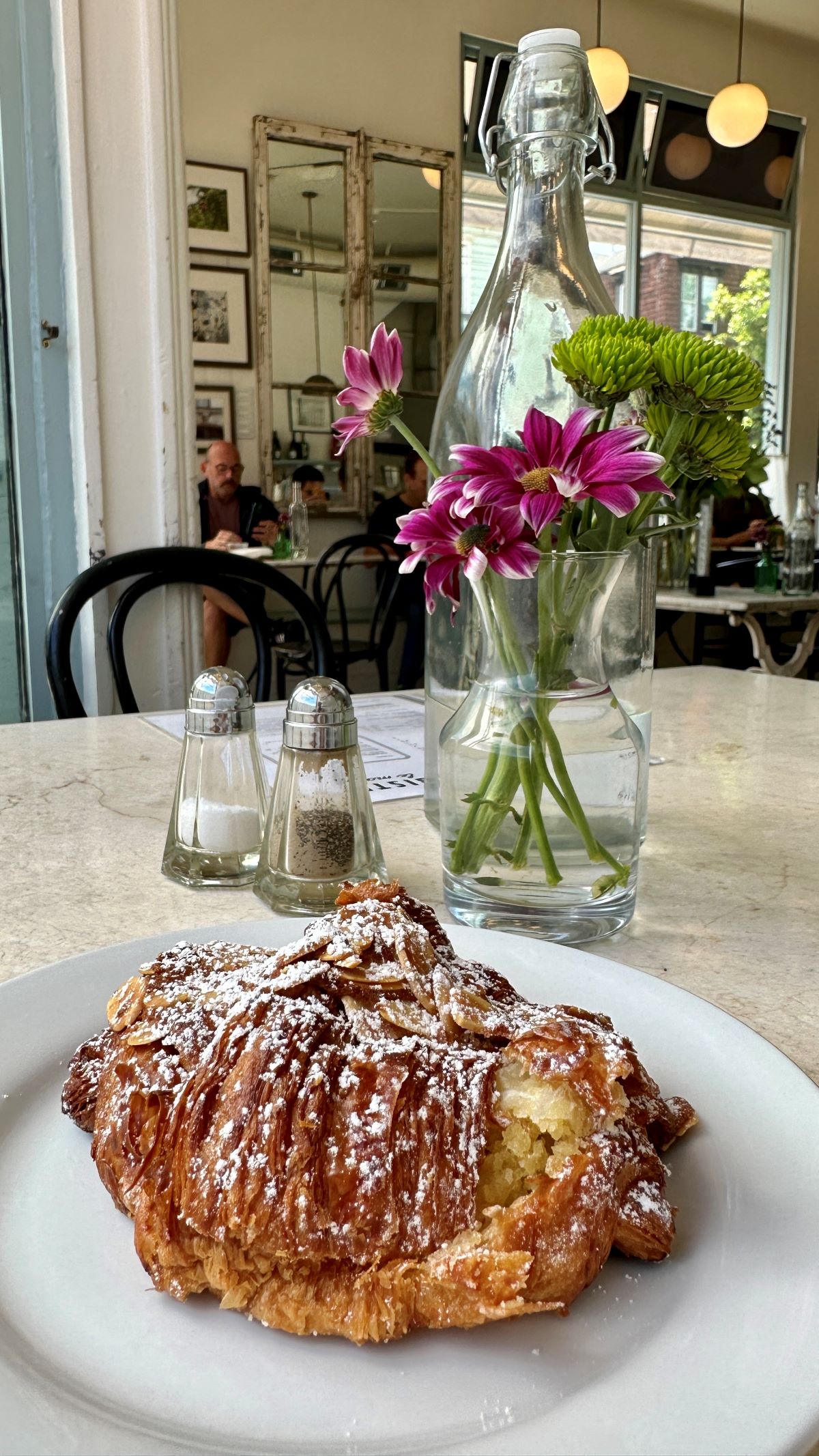 Closeup of croissant and in the background is a flower in a vase.
