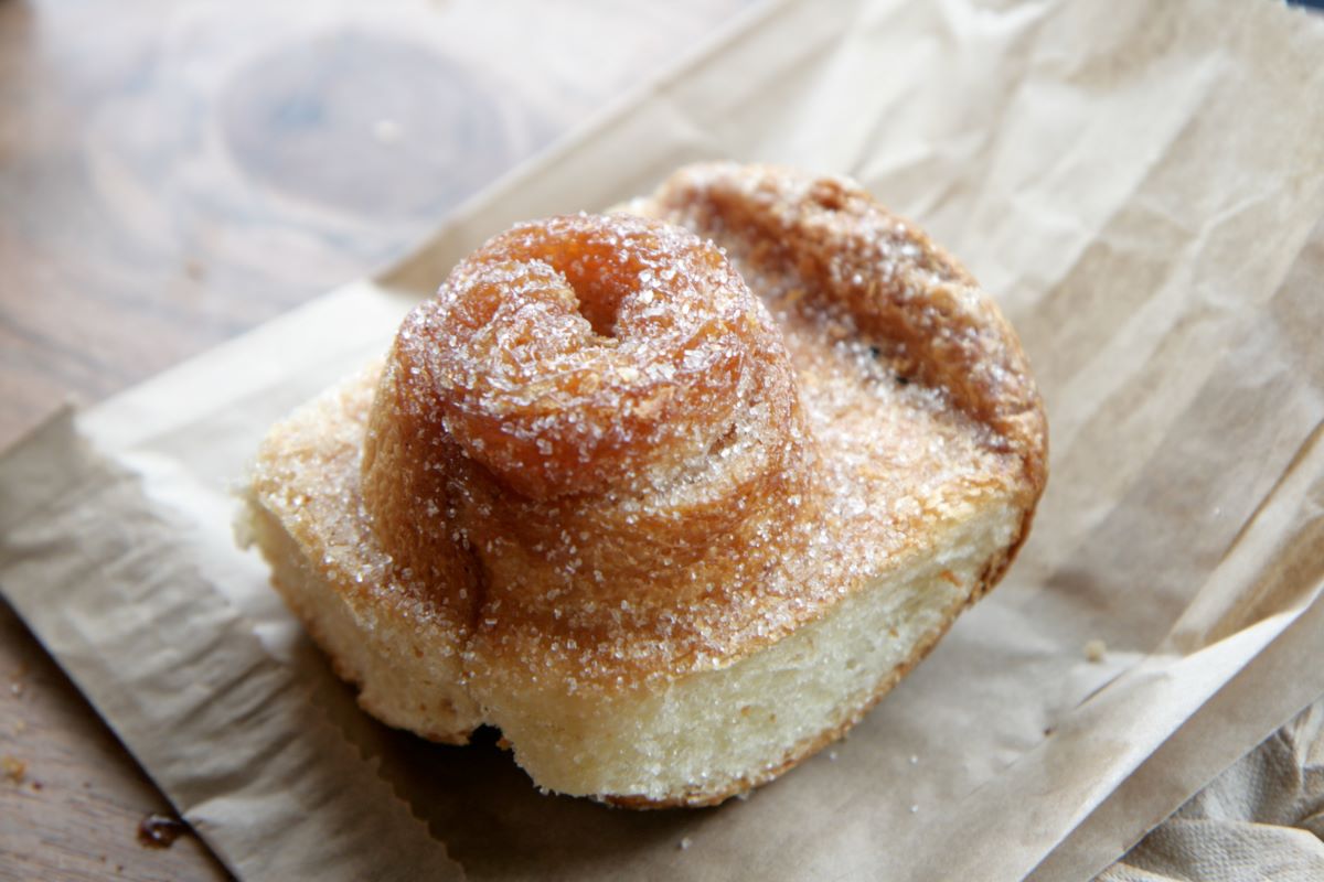 Closeup of sugared bun pastry that sits on top on a paper bag.