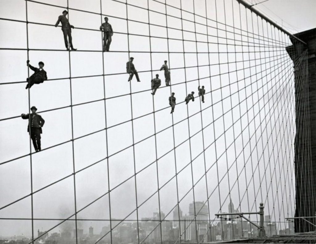 back and white photo of men standing on steel cables