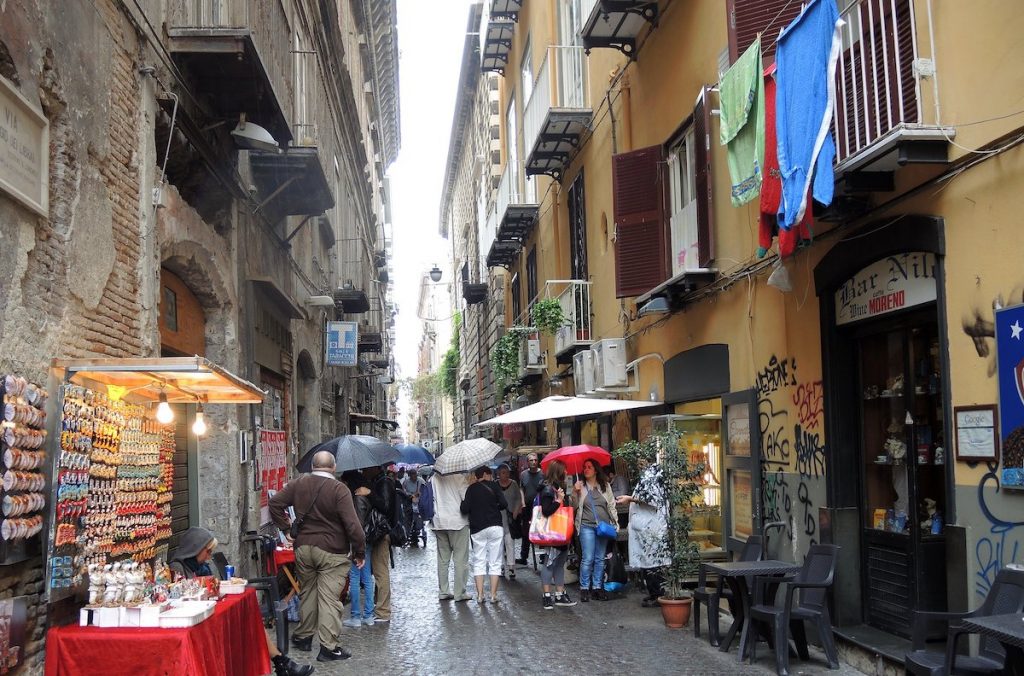 People walking on a busy street in Naples, Italy during a rainy day