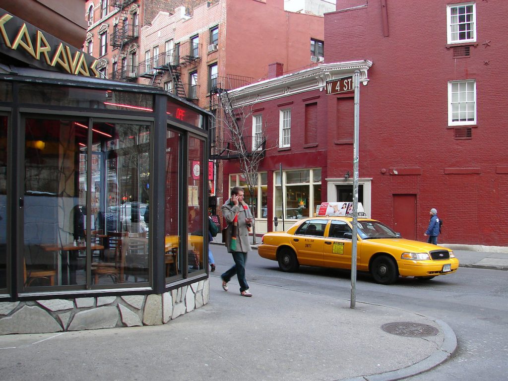 man walking on a street in nyc with a taxi nearby