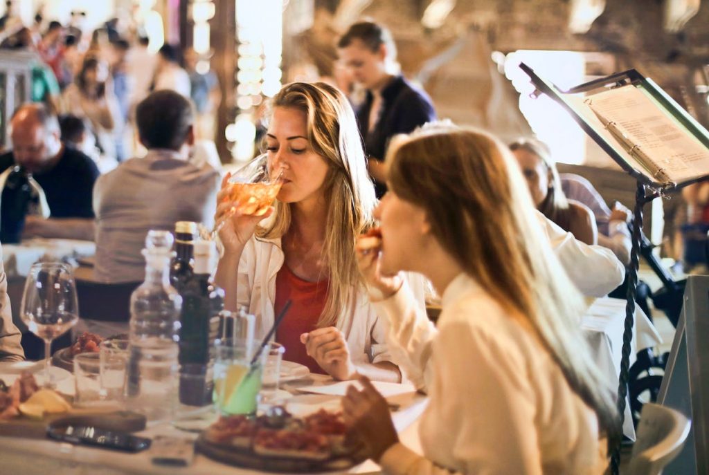 Women eating and drinking Italian food in a terrace