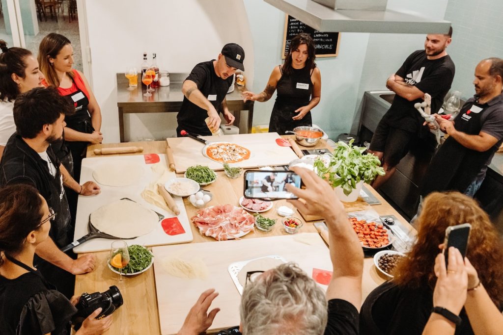 a group of people learning to make traditonal italian pizza in a class