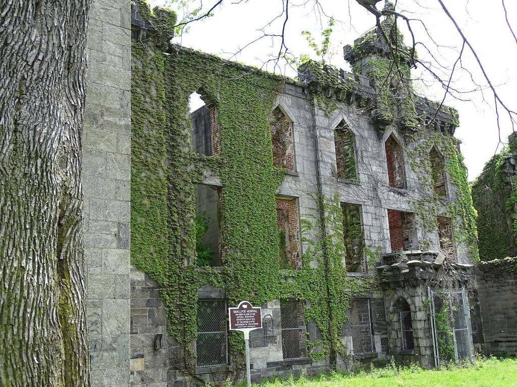 ruins of hospital with vines growing around it